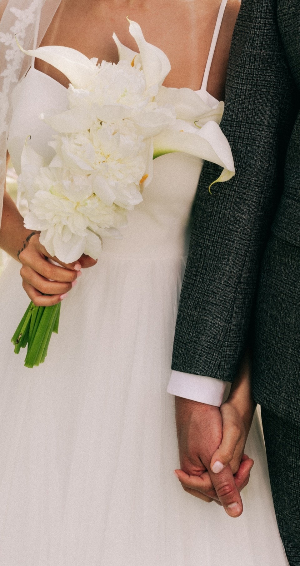 Newlyweds holding hands with a white bouquet