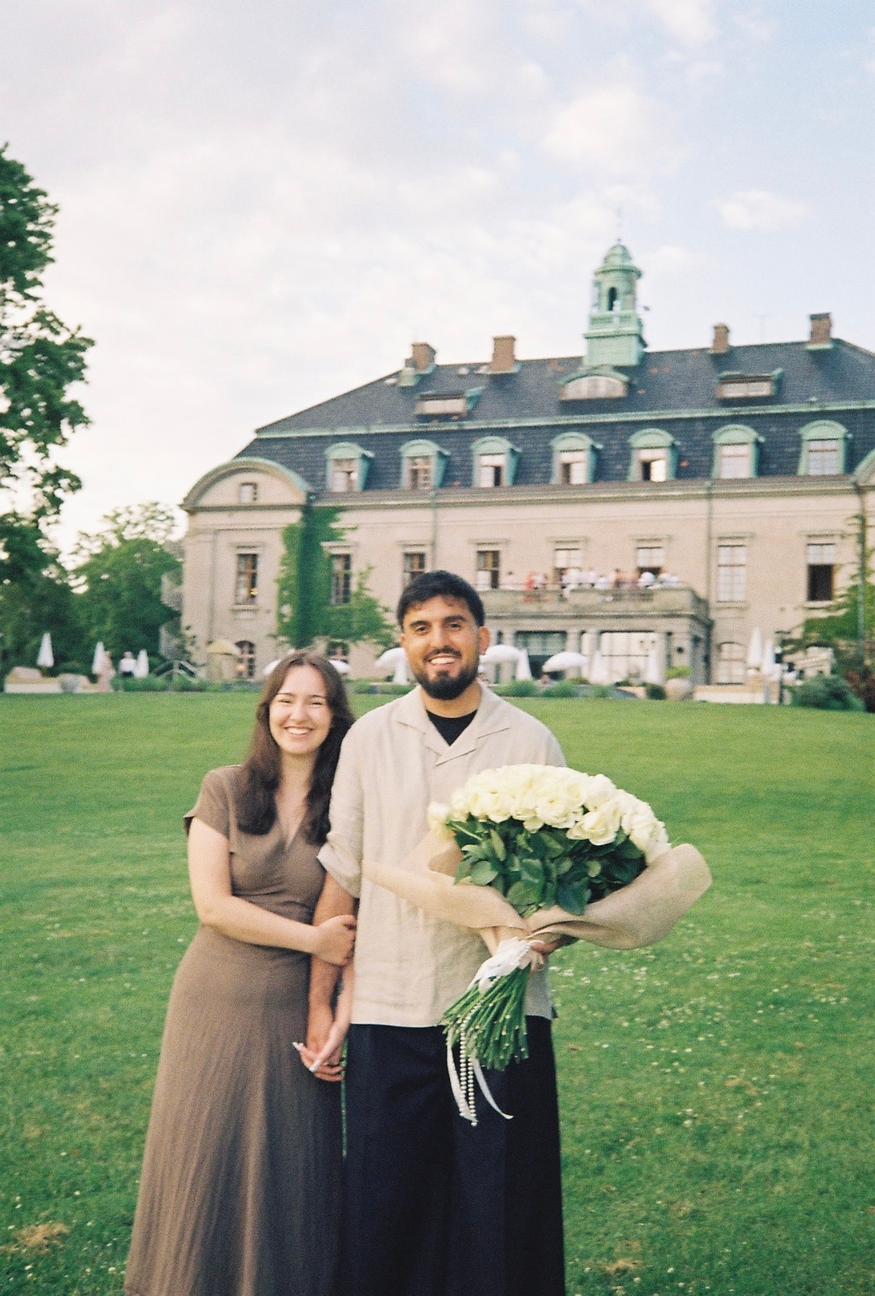 Zana og Anela, parret bag Par Studio, foran en herregård med en hvid rosenbuket